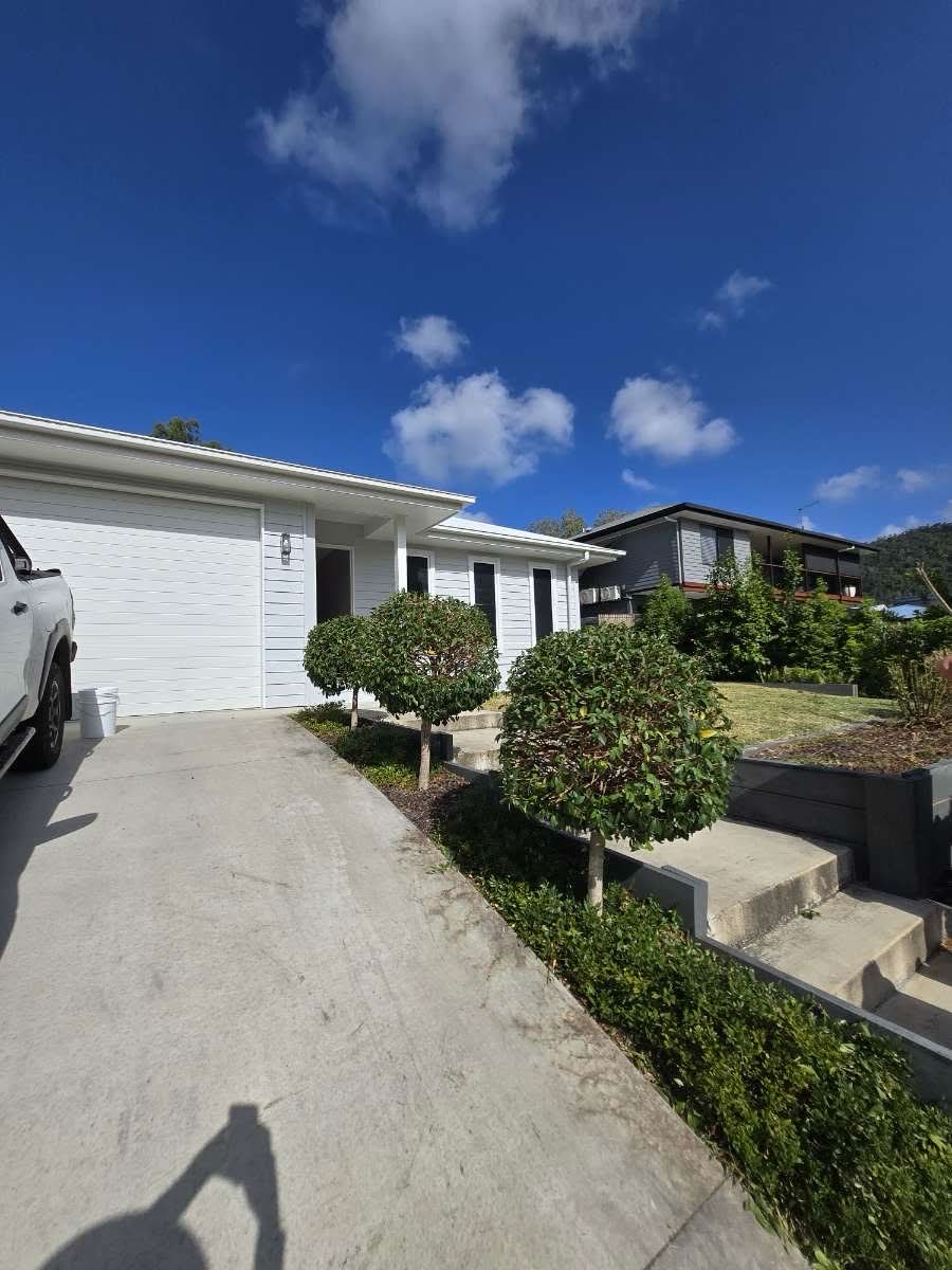 Neatly pruned topiary shrubs lining a residential driveway in Airlie Beach