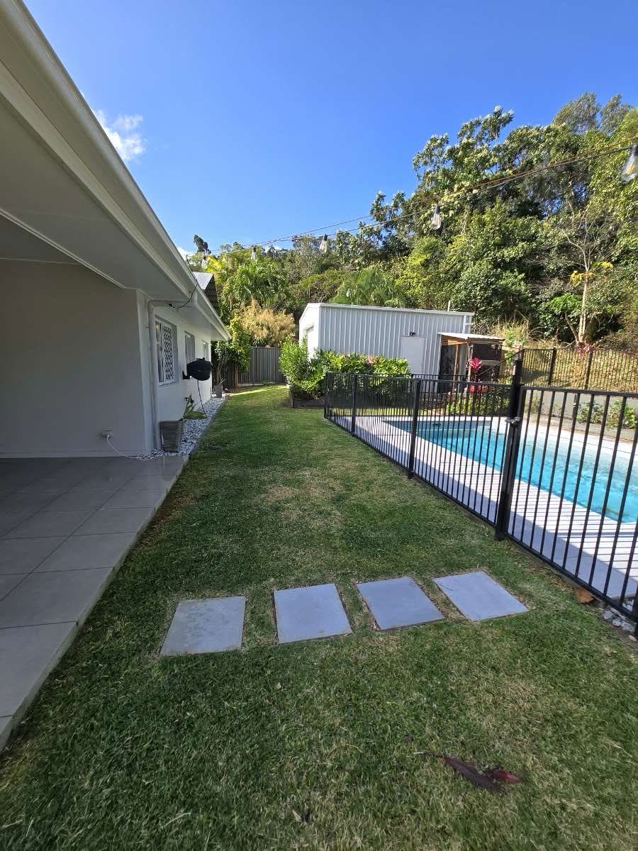 Tidy backyard garden with manicured lawn beside a pool fence